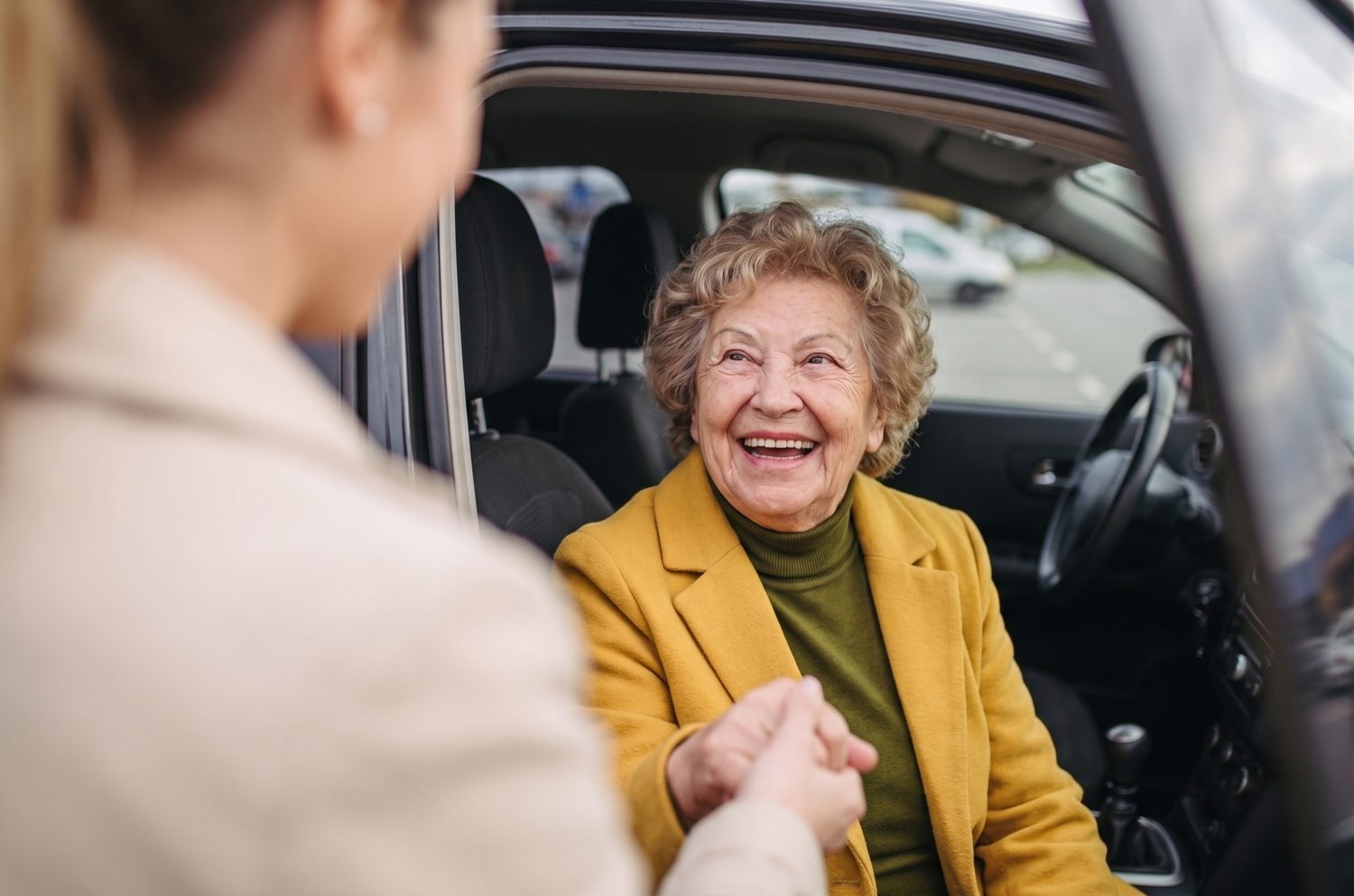 Adulta mayor sonriente en el auto siendo recibida con cariño